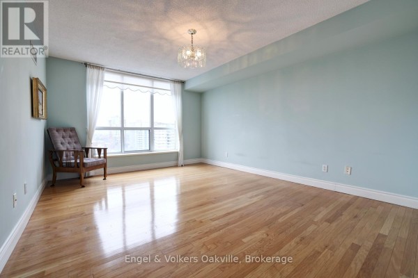 Living room with hardwood floors, large window, and armchair - 1402 - 442 Maple Avenue Burlington