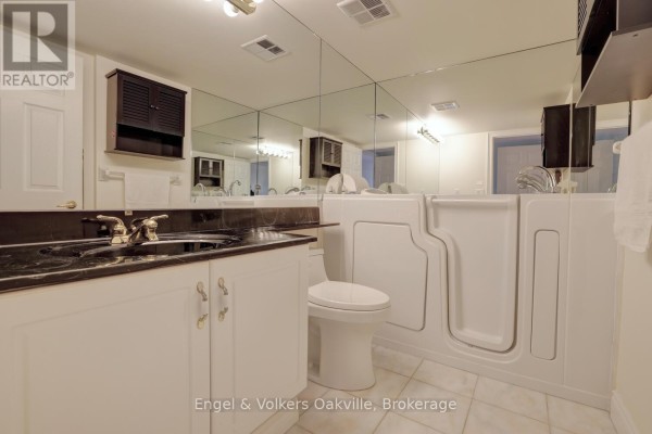 Bathroom with walk-in bathtub, vanity, and mirrored wall - 1402 - 442 Maple Avenue Burlington