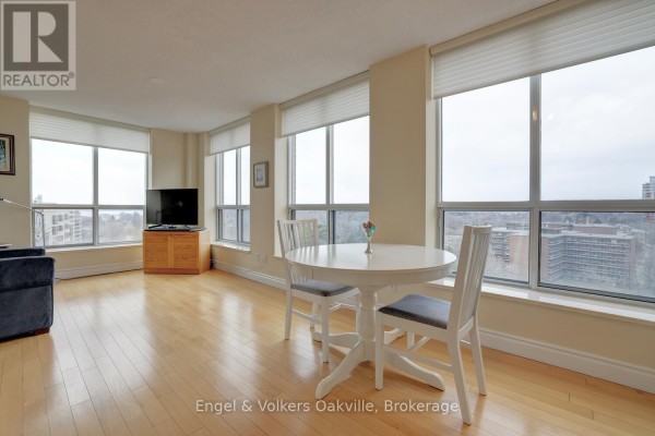 Living/dining area with round table, chairs, TV, and hardwood floors - 1402 - 442 Maple Avenue Burlington