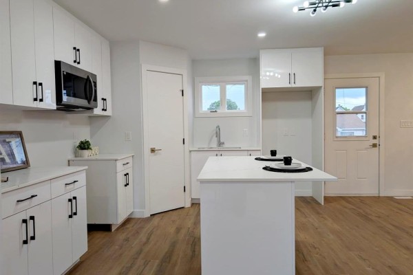 Living room with large window, light-colored walls, and laminate flooring. - 1402 Pacific Avenue, Winnipeg
