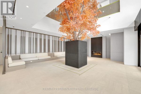 Building lobby features a large artificial tree with orange leaves and modern seating. - 1403 - 4015 The Exchange, Mississauga