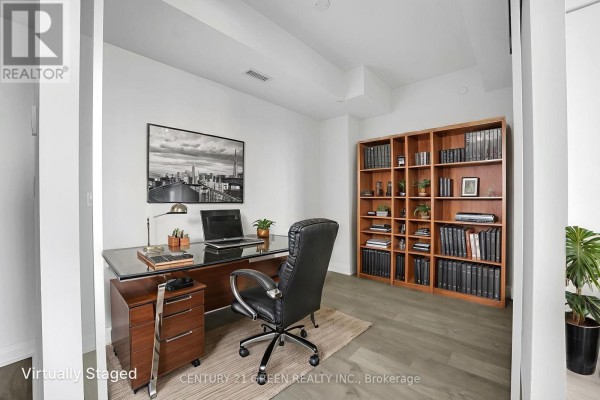 A home office with a wooden desk, leather chair, laptop, and a large bookshelf. - 1403 - 4015 The Exchange, Mississauga