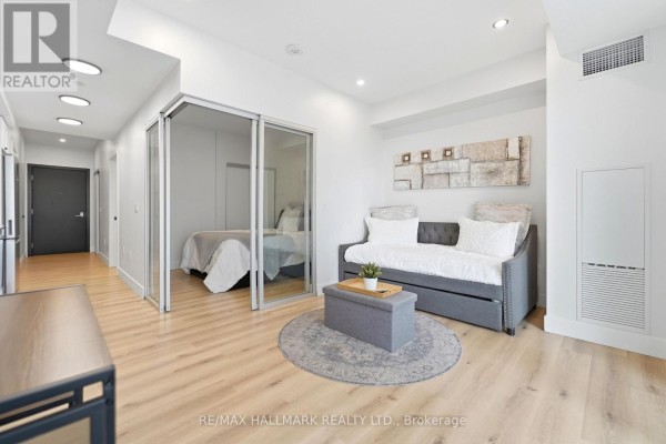 View of a studio apartment showing the living area with a sofa bed and a glimpse of the bedroom through glass doors. - 1403 - 5 Wellington Street S, Kitchener