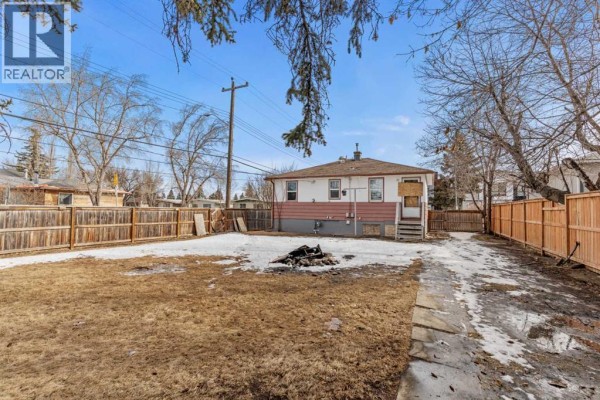 View of the backyard from a different angle, showing the house and fencing. - 1403 43 Street Sw, Calgary