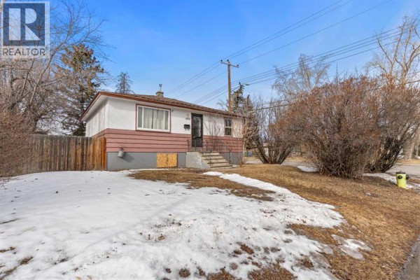 Front exterior of the house with snow, grass, and shrubs. - 1403 43 Street Sw, Calgary