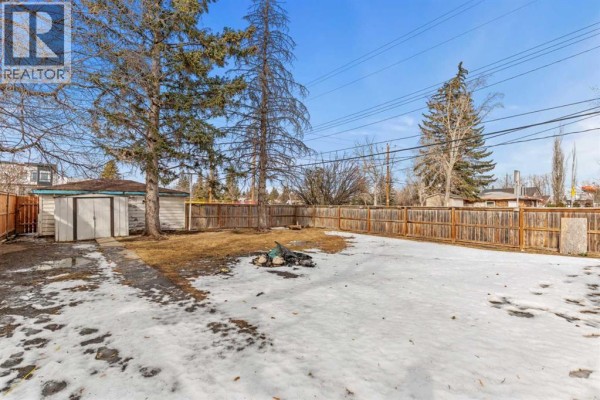 Backyard view featuring a shed, snow, and wooden fencing. - 1403 43 Street Sw, Calgary
