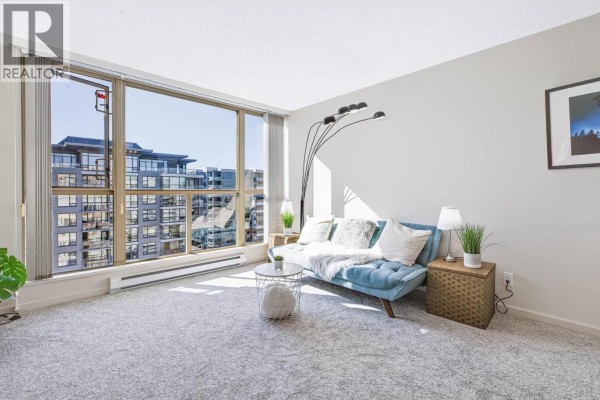 Living room with a blue sofa, white rug, and large window overlooking city buildings. - 1403 8171 Saba Road, Richmond
