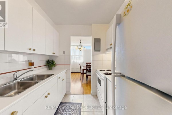 White kitchen with stainless steel double sink, white cabinets, and a white stove. - 1404 - 1455 Lawrence Avenue W, Toronto