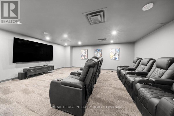 Home theatre room with rows of reclining chairs facing a large screen television. - 1404 - 161 Laurier Avenue W, Ottawa