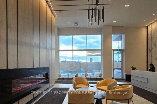 Apartment building lobby with a modern fireplace, seating area, and large windows. - 1404 - 260 Malta Avenue, Brampton