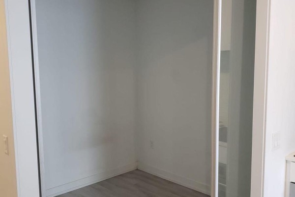 Empty room with white walls and sliding closet doors, showing a view of a light grey floor. - 1404 - 33 Helendale Avenue, Toronto