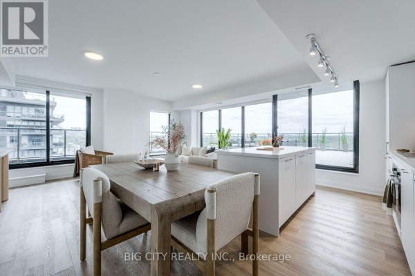 Dining area and open-concept kitchen with white island and light wood floors. - 1404 - 36 Brentcliffe Road, Toronto