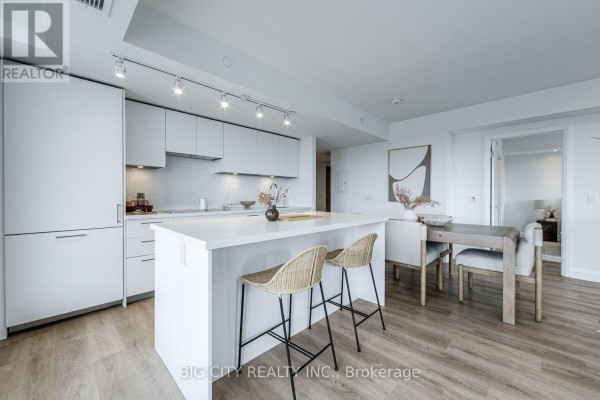 Open-concept kitchen and dining area with white cabinetry, island, and natural light. - 1404 - 36 Brentcliffe Road, Toronto