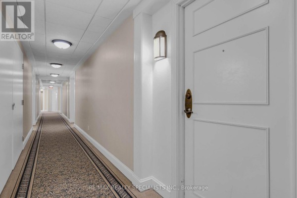 Long corridor with beige walls, overhead lighting, and a patterned carpet. - 1404 - 710 Humberwood Boulevard, Toronto