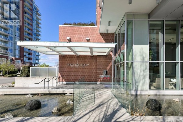 Entrance to a modern building with glass awning and brick accents. - 1404 83 Saghalie Rd, Victoria