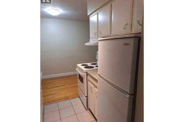 Kitchen with white cabinets, refrigerator, stove, and hardwood floors. - 1404 E 57th Avenue, Vancouver