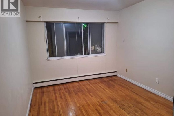 Interior room with hardwood floors, neutral walls, and a large window. - 1404 E 57th Avenue, Vancouver