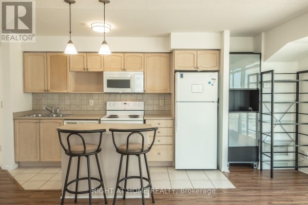 Kitchen with light wood cabinets, white appliances, tile backsplash, refrigerator, and shelving unit. - 1405 - 18 Yonge Street, Toronto