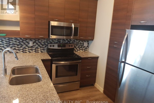 Close-up of a stove and microwave in a kitchen with dark wood cabinets and a tiled backsplash. - 1405 - 318 Spruce Street, Waterloo