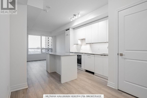 Open concept living area with a white kitchen and a large island. - 1405 - 36 Elm Drive W, Mississauga