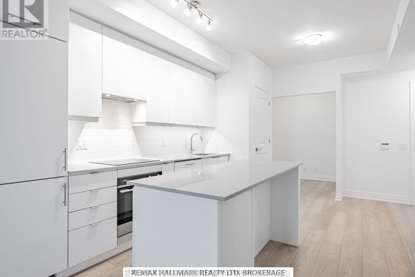 Kitchen with white cabinetry, quartz countertop island, and light wood flooring. - 1405 - 36 Elm Drive W, Mississauga