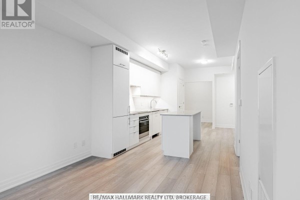 Bright living space with white walls, light wood floors, and a modern kitchen. - 1405 - 36 Elm Drive W, Mississauga