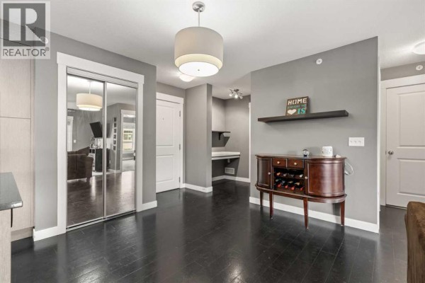 Apartment entryway with dark wood floors, mirrored closet doors, and a wine cabinet. - 1406, 240 Skyview Ranch Road Ne, Calgary