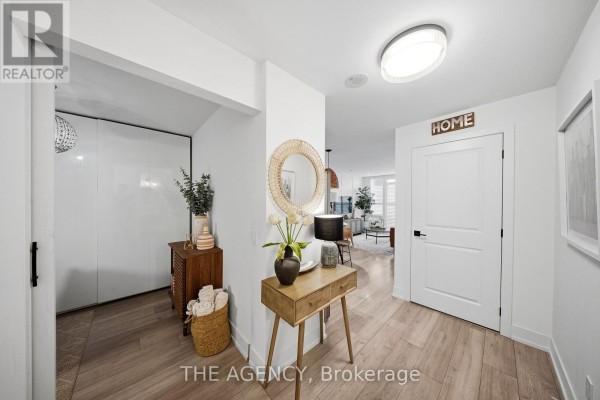 Apartment hallway with wood flooring, a console table, and open doorway to living area. - 1406 - 1215 Bayly Street, Pickering