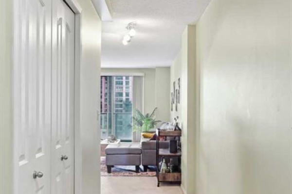 Hallway looking towards the living area, featuring a closed closet door and cream walls. - 1407, 1111 6 Avenue Sw, Calgary