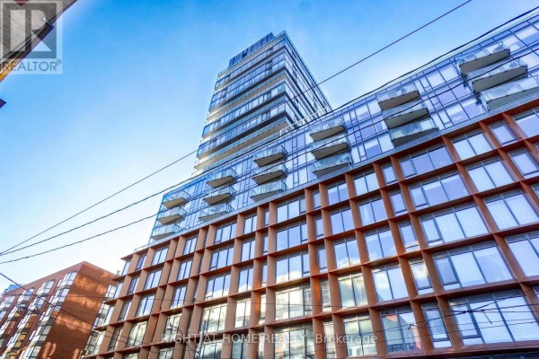 A building facade with repeating glass windows and balconies against a bright blue sky. - 1407 - 60 Colborne Street, Toronto