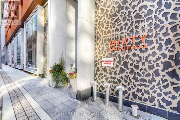 Exterior building entrance with textured metal panels, planters, and fire department connection. - 1407 - 60 Colborne Street, Toronto