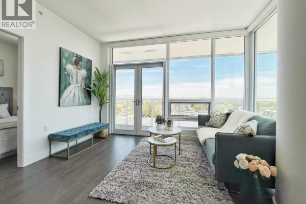 Living room with a teal sofa, bench, and large windows overlooking a cityscape. - 1407 6328 No. 3 Road, Richmond