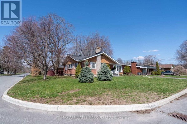 Wide angle view of a bungalow on a corner lot with a green lawn and trees. - 1407 Boyd Street S, Cornwall