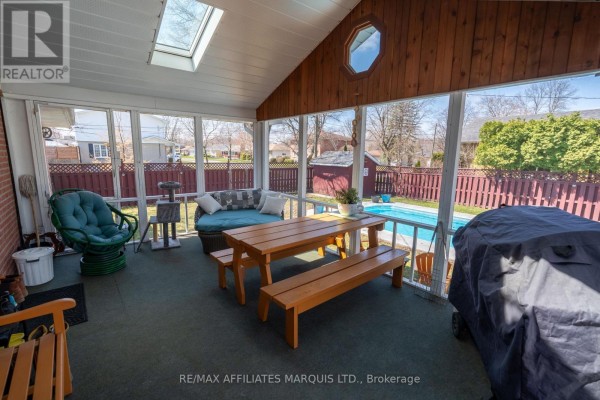 Sunroom with a sofa, picnic table, pool view, and BBQ grill on the right. - 1407 Boyd Street S, Cornwall