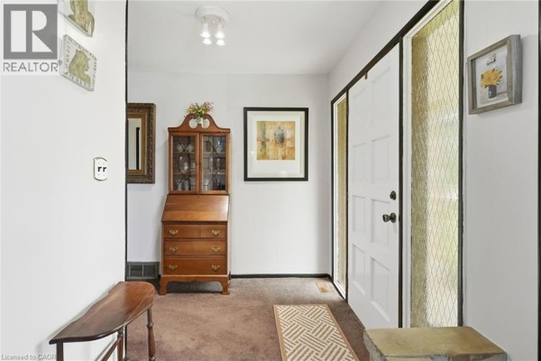 Interior entryway with white walls, brown carpet, wood secretary desk, and a white bench. - 1408 Edgewood Road, Flamborough