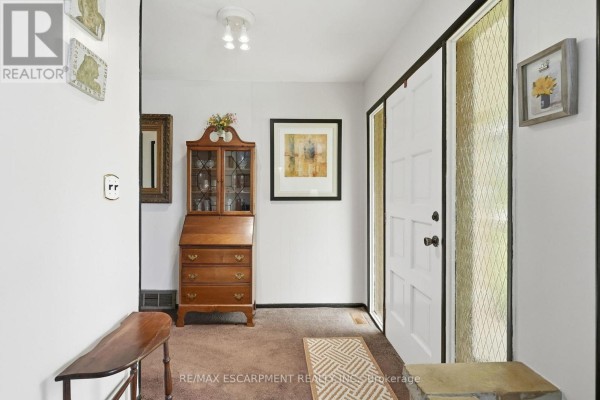Interior foyer with a wooden desk, bench, artwork, and white door. - 1408 Edgewood Road, Hamilton