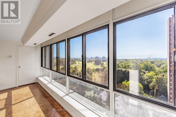 Sunroom with parquet flooring and expansive windows overlooking a golf course and trees. - 1409 - 1400 Dixie Road, Mississauga