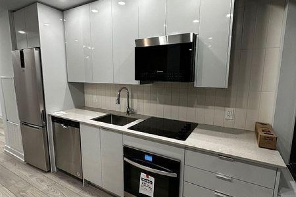 Close-up of the kitchen showing a stainless steel refrigerator, dishwasher, induction cooktop, oven, and microwave. - 1409 - 2920 Hwy 7, Vaughan