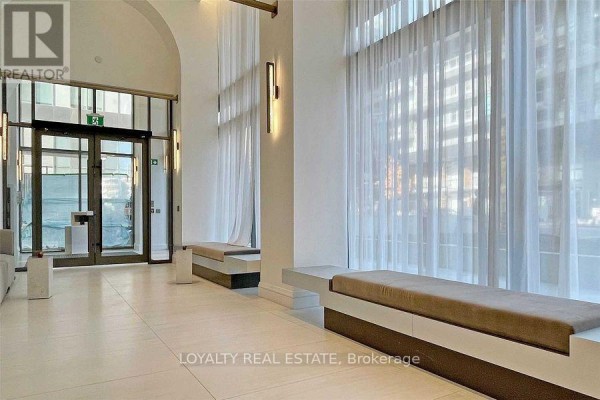 Building lobby with beige tile floor, seating benches, and large sheer curtains. - 1409 - 39 Roehampton Avenue, Toronto