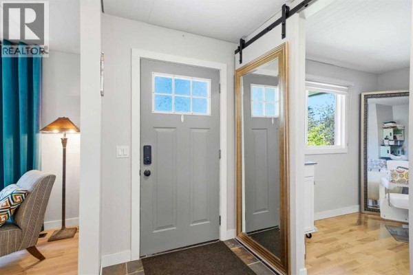 Interior foyer with a grey door, large gold mirror, and a seating area. - 1409 Idaho Street, Carstairs