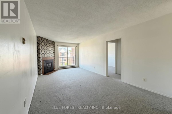 Living room with grey carpet, white walls, and an opening to another room. - 141 - 1096 Jalna Boulevard, London South