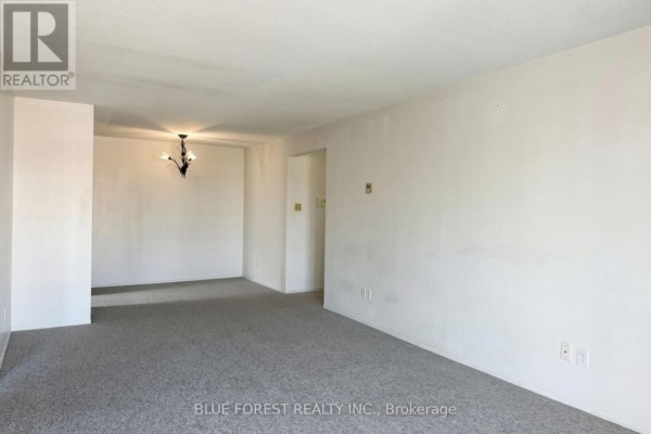 Empty living and dining room with beige walls, grey carpet, and a chandelier. - 141 - 1096 Jalna Boulevard, London South