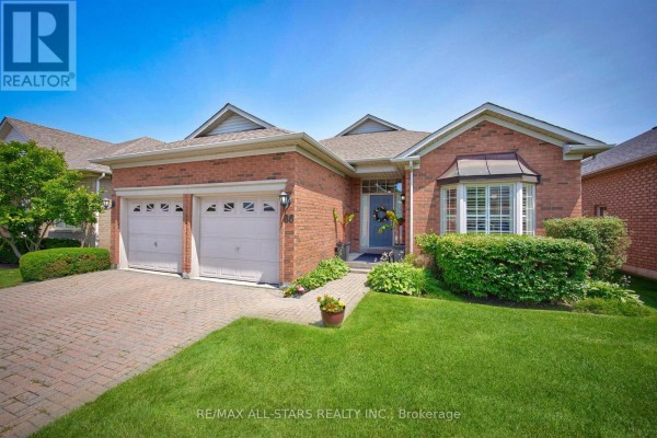 Front exterior of a brick house with two garage doors, a bay window, and landscaping. - 141 - 86 Legendary Trail, Whitchurch Stouffville