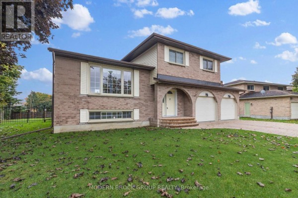View of the front right side of a brick house with a bay window and dual garage doors. - 141 Beley Street, Brockville