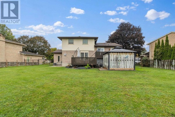 Rear exterior view of a two-story house with a wooden deck, gazebo, and fenced yard. - 141 Beley Street, Brockville