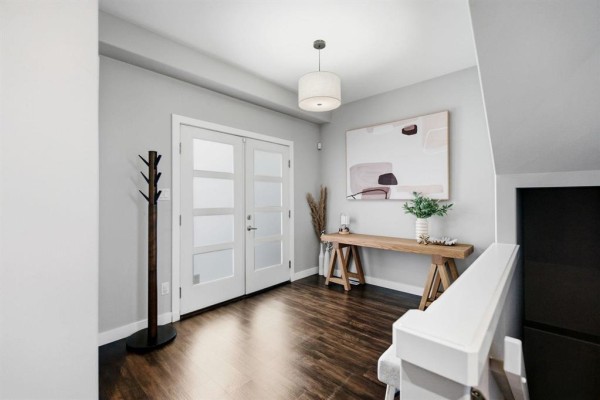 Bright entryway with glass-paneled double doors, wooden console table, and abstract art. - 141 Daylan Marshall Gate, Winnipeg