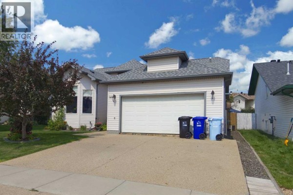 Exterior front view of a house with light siding, a double garage door, and a driveway. - 141 Eglert Drive, Fort Mcmurray