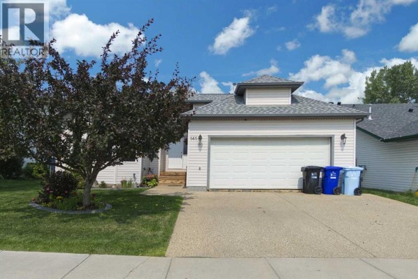 Front view of the house with a double garage door, a driveway, and a small tree. - 141 Eglert Drive, Fort Mcmurray