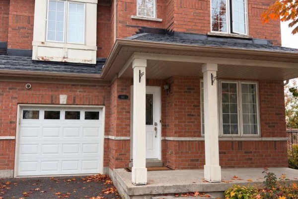 Front exterior of a two-story brick house with a white garage door and covered front entrance. - 141 Gail Parks Crescent, Newmarket