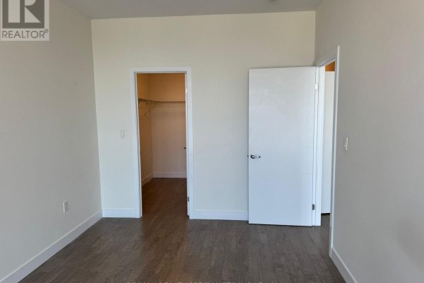 Bedroom with two doors, one opening to a closet with shelving. - 1410 - 100 Garment Street N, Kitchener